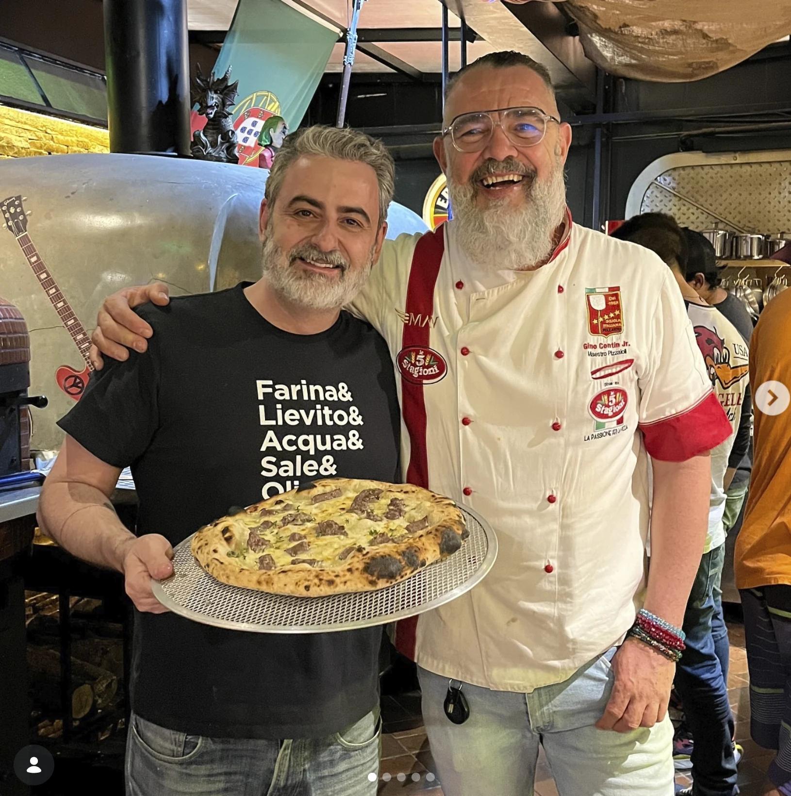 Leo Nelli e o Maestro Gino Contin posam com uma pizza diante de um forno.